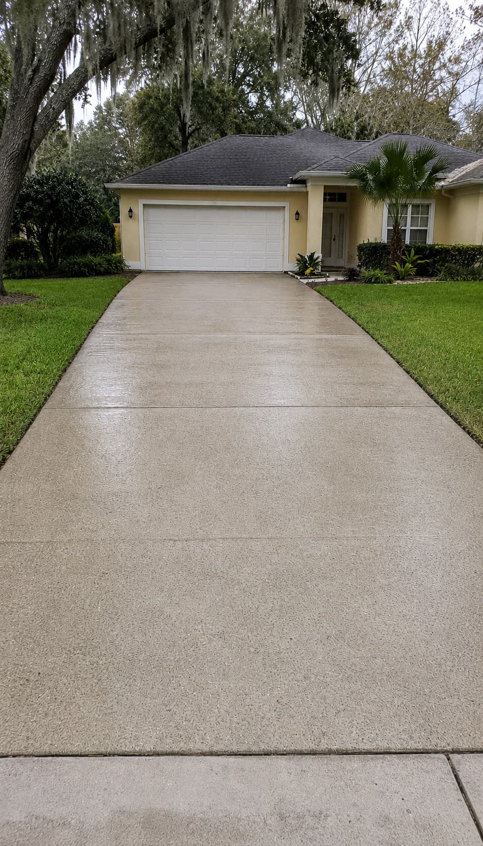 Same residential concrete driveway after professional pressure washing — cleaned to a realistic aged-Florida-concrete finish